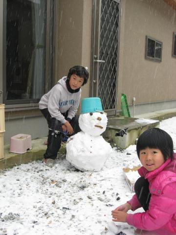 雪だるまを作る啓作と雪うさぎを作るみさ